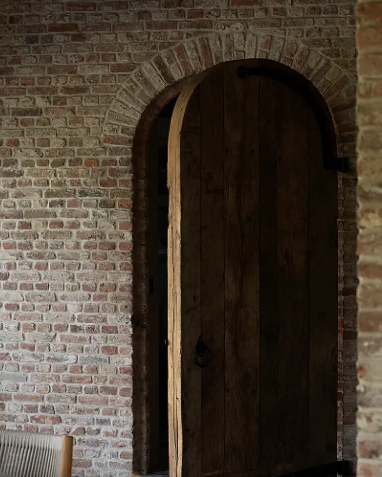 Oude eiken poort in een boog van baksteen, met een vloer in oude kasseien
