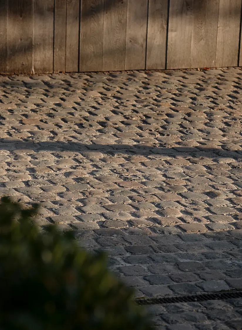 Oude kasseien in warm strijklicht voor een wand van houten planken